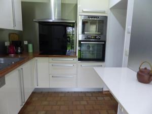 a kitchen with white cabinets and a stove top oven at Maison de campagne in Touchay