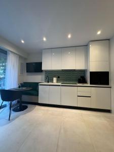 a kitchen with white cabinets and a table in it at Cosy apartment with shared pool and garden in Athens