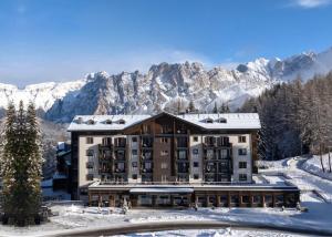 a hotel with snow covered mountains in the background at Hotel Tofana Cortina in Cortina dʼAmpezzo
