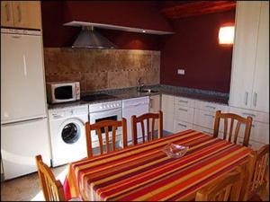 a kitchen with a table with chairs and a stove at La Venta Vieja de Langre in Langre