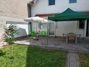 a patio with a table and a green umbrella at Apartments Košević in Osijek
