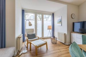 a living room with a tv and a chair and a window at Sünnslag 103 - "Ferienhaus Ostseezauber" - 4 Zimmer, im Herzen Boltenhagens in Boltenhagen +26 photos