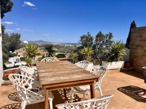 a wooden table and white chairs on a patio at Casa Ibicenca - Precioso chalet con piscina in Peñíscola