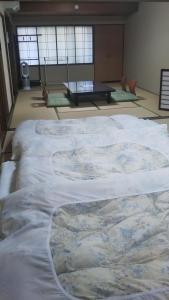 a large white bed in a room with a table at Kikunoya Ryokan in Kanazawa