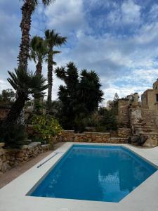 a swimming pool in a yard with palm trees at Ta' Tereża Farmhouse in Xagħra