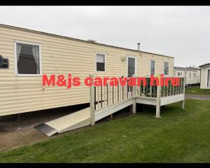 a mobile home with a deck and a sign on it at M&js caravan hire in Kinmel Bay