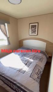 a bedroom with a bed and a window at M&js caravan hire in Kinmel Bay +5 photos