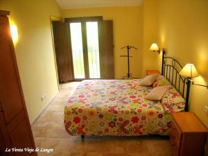 a bedroom with a bed with a floral comforter at La Venta Vieja de Langre in Langre