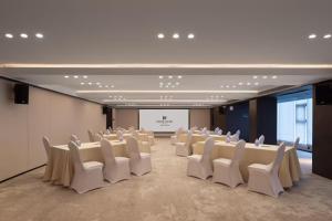 a conference room with white chairs and a screen at 中濠悦际酒店 深圳国际会展中心店 in Shenzhen