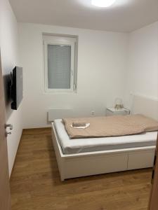バラトンボグラールにあるAA Apartman - Balatonboglárのベッドと窓のある白い部屋