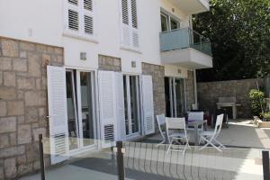 Casa con ventanas blancas, mesa y sillas en Apartments Mala, en Cavtat