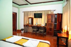 a hotel room with a bed and a desk and a television at Vang Vieng Mountain View Hotel in Vang Vieng