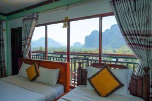 two beds in a room with a balcony with mountains at Vang Vieng Mountain View Hotel in Vang Vieng
