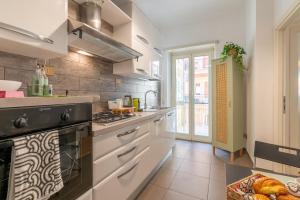 een keuken met witte kasten en een kookplaat oven bij Gemelli Apartment in Rome