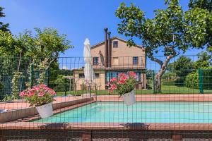 a swimming pool with two potted plants and a house at Country House La Fattoria Di Paolo in Treia