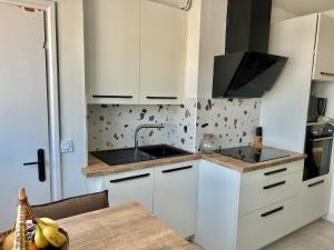 kuchnia z białymi szafkami, zlewem i stołem w obiekcie Jolie vue- T2 Centre -by Breizh key w mieście Lorient