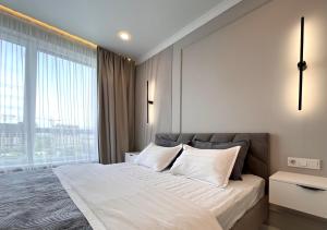Un dormitorio con una cama grande y una ventana grande. en Новая Раимбек Резиденс 13-65 & питьевая вода в подарок, en Almaty