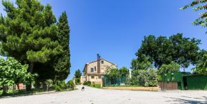 a house in the middle of a dirt road with trees at Country House La Fattoria Di Paolo in Treia