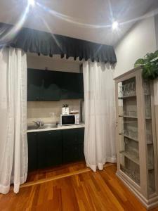 una cucina con tende bianche, un lavandino e un microonde di Next Stop Vatican Guest House a Roma Altre 15 foto