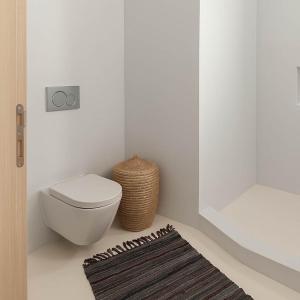 a white bathroom with a toilet and a rug at Rustic Stone House in the Heart of Folegandros in Áno Meriá