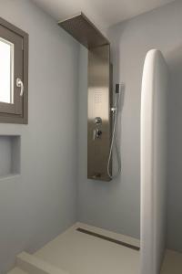 a bathroom with a shower in a white wall at Rustic Stone House in the Heart of Folegandros in Áno Meriá
