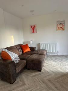 a living room with a brown couch and orange pillows at Casa Sands in Spittal