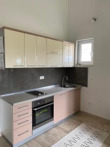Una cocina con gabinetes blancos, un fregadero y una estufa. en MARSHAL Apartments, en Donji Štoj 3 fotos más