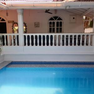 a swimming pool in front of a house with a fence at Villa Baywalk Goa - 200 meters from Morjim Beach in Morjim