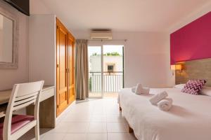 a bedroom with a bed and a desk and a window at Hostal Marí in San Antonio