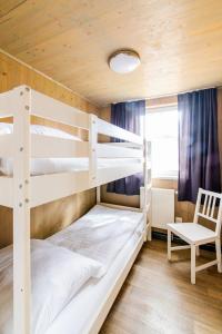 a bedroom with two bunk beds and a chair at Naturcamping Lüneburger Heide - Chalets & Tiny Häuser in Soltau