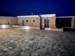 a stone patio in front of a building at night at Rustic Stone House in the Heart of Folegandros in Áno Meriá