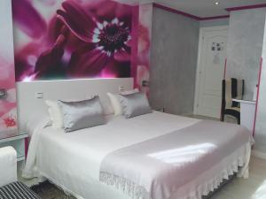 a bedroom with a white bed with a flower painting on the wall at El Jardin in Soto de la Marina +74 photos