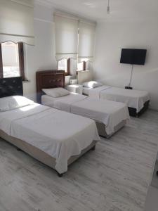 a hotel room with three beds and a flat screen tv at Edirne ulus home 10 rooms in Edirne