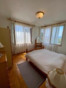 a bedroom with a large bed and two windows at Lilys Paradise in Orebić