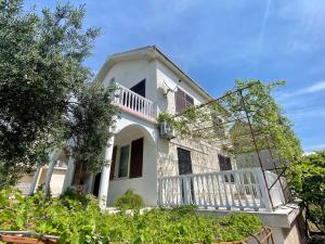 a white house with a balcony and trees at Lilys Paradise in Orebić