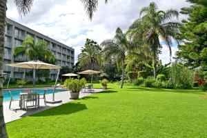 a resort with a pool and a lawn with tables and umbrellas at Holiday Inn - Bulawayo by IHG in Bulawayo