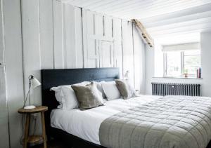 une chambre avec un grand lit avec des draps et des oreillers blancs dans l'établissement River Cottage HQ, à Musbury