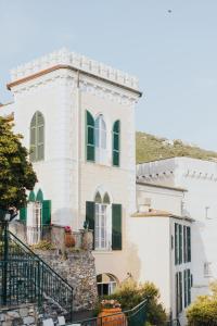 a white house with green shutters on a hill at Castello Canevaro in Zoagli +90 photos