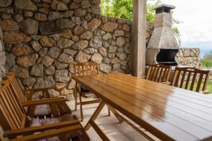 a wooden table and chairs in front of a stone wall at Villa Grkasha in Ohrid
