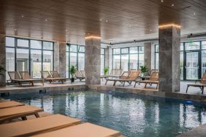 马马亚Rayan Apartment in Odyssey Spa Pool & Fitness-parking的建筑物内设有带桌椅的游泳池