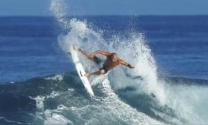 a man riding a wave on a surfboard in the ocean at MMMpulukansurfvilla in Medewi