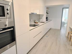a kitchen with white cabinets and a stove top oven at Grey and Green, modern 2-bedroom apartment, AC, top location at faro's historic centre in Faro