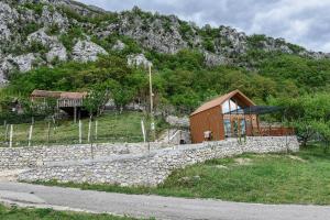 a building with a stone wall next to a mountain at Ostrog Wood House in Železnička Stanica Dabovići