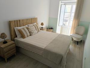 a bedroom with a bed with a chair and a window at Grey and Green, modern 2-bedroom apartment, AC, top location at faro's historic centre in Faro