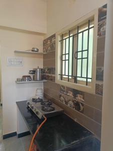 a kitchen with a stove and a window in it at Anugrahaa family Roomstay in Tiruchchirāppalli