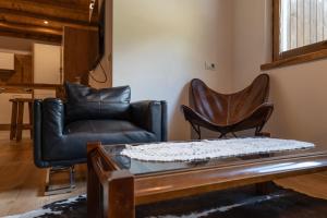 a living room with two leather chairs and a coffee table at Mountain Dolomiti Apartments-Maison Perrod in Predazzo