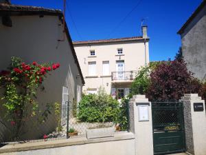 a white building with a gate and red flowers at Les Ombelles in Saint-Estèphe