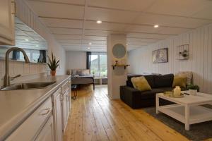 una cucina e un soggiorno con divano di Detente Nature bord de Lac #1 Spa Sauna & Foyer a Sainte Brigitte de Laval