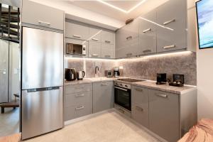 a kitchen with white cabinets and a stainless steel refrigerator at September15 Suites, Lefkada-Episkopos in Nikiana