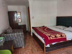 a bedroom with a bed and a chair in it at Sandeep homestay in Dharamshala